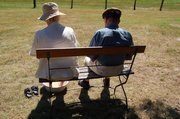Foto, das ein älteres Paar auf einer Bank zeigt, das Abkühlung sucht
