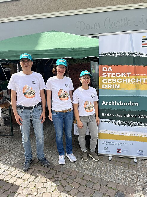 Drei Personen neben einem Rollup
