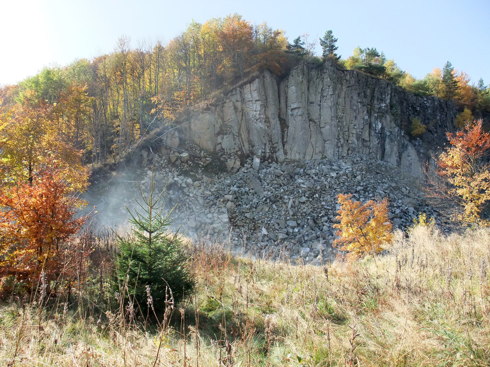 Die sogenannte „Stinksteinwand“ mit Rauchwolken schwelender Braunkohlenflözen unterhalb des Basaltes